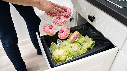 foto dat iemanand eten weggegooid in een container